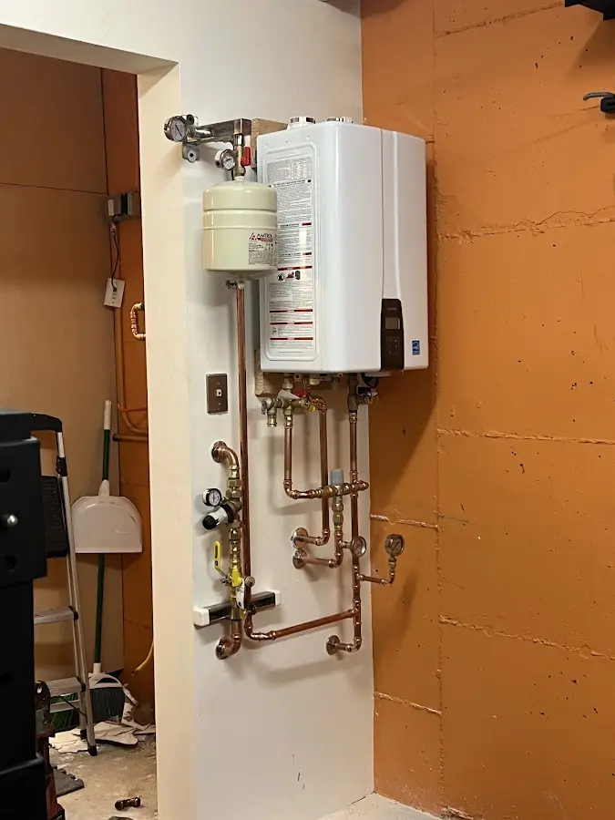 Plumbing technician inspecting water heater connections in East Alton